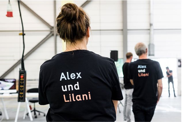 Zwei abgewandte Personen und auf dem Rücken der T-Shirts steht Alex und Lilani geschrieben.