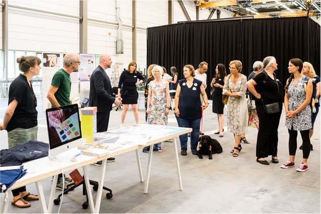 Man sieht das Publikum, das der Präsentation in der Halle des SCHD folgt